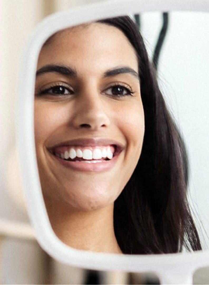 teeth-whitening2 woman smiling into a mirror